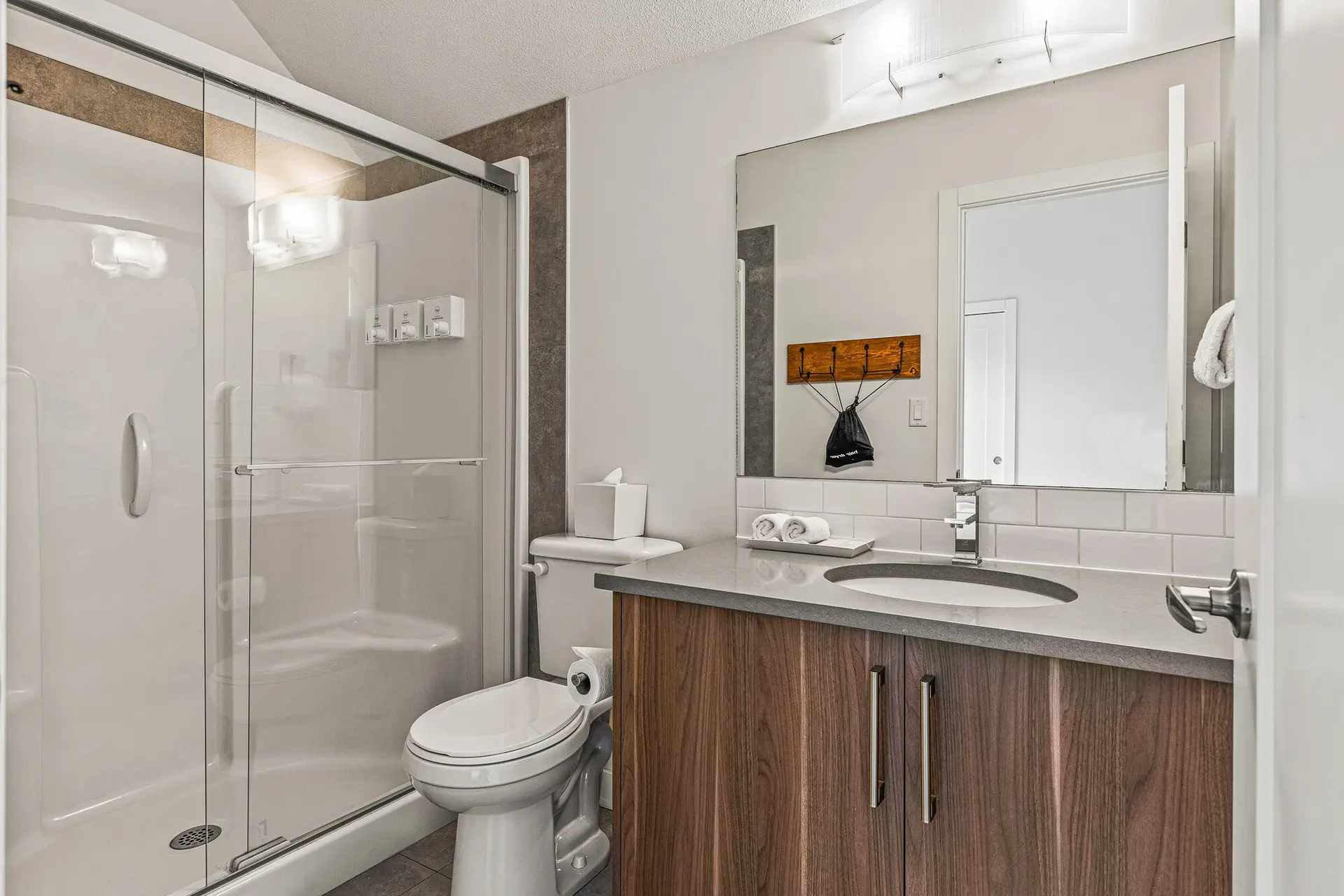 Bathroom with glass shower, toilet, sink, and wooden cabinets