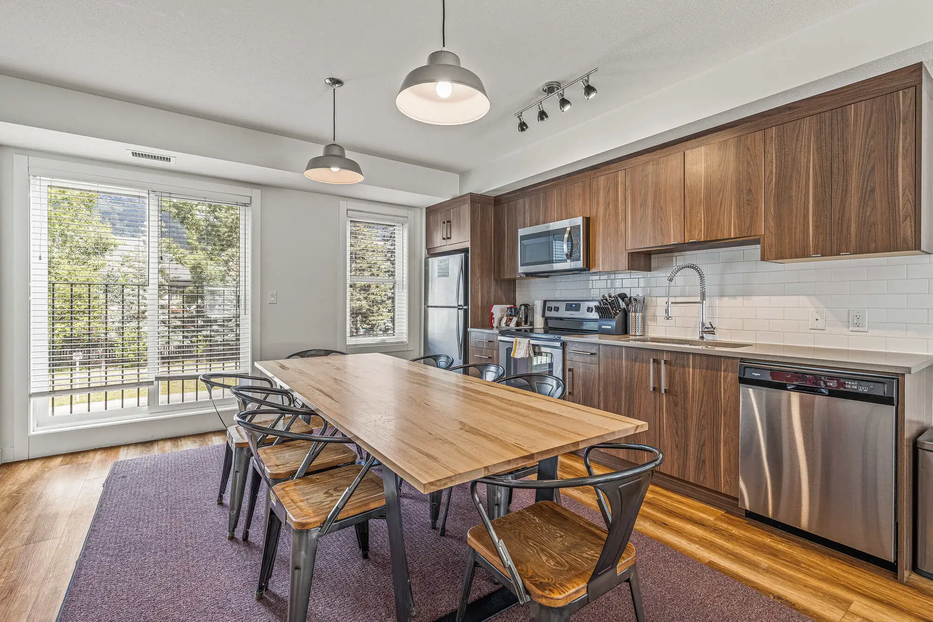 Basecamp Resorts Canmore three-bedroom suite dining and kitchen area with wooden table and chairs.