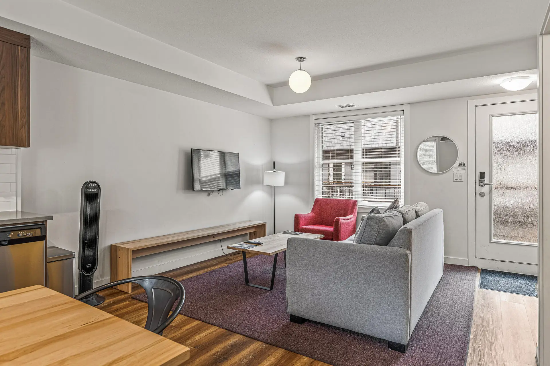 Living area of a Basecamp Resorts Canmore three-bedroom suite with sofa, armchair, and TV.
