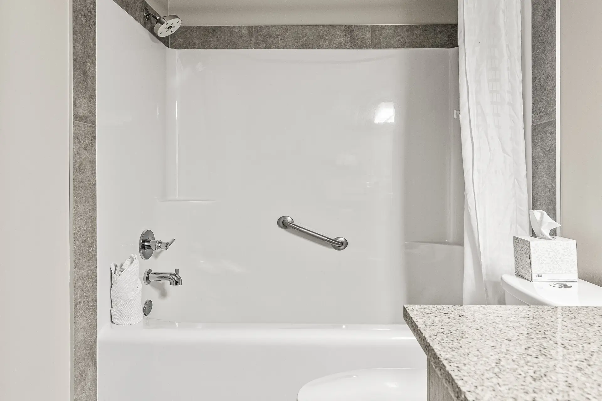 Deluxe Double Queen room bathroom at Basecamp Lodge Canmore, featuring a white bathtub, shower, and grab bar.