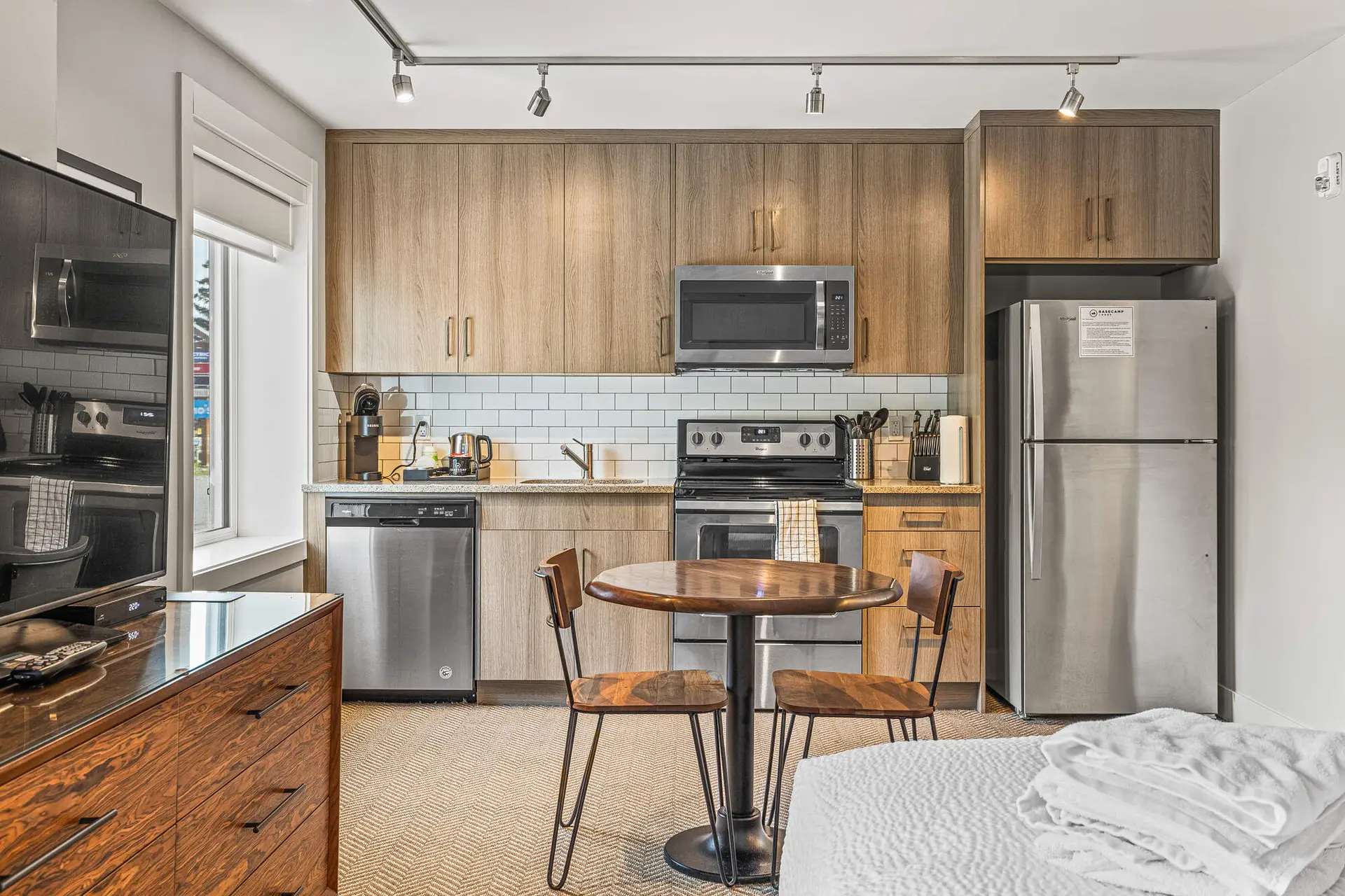 Basecamp Lodge Canmore micro suite kitchen with dining area and TV.