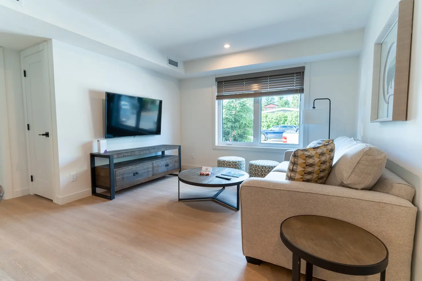 Living room of a Basecamp Suites Canmore three-bedroom apartment with sofa, coffee table, and TV.