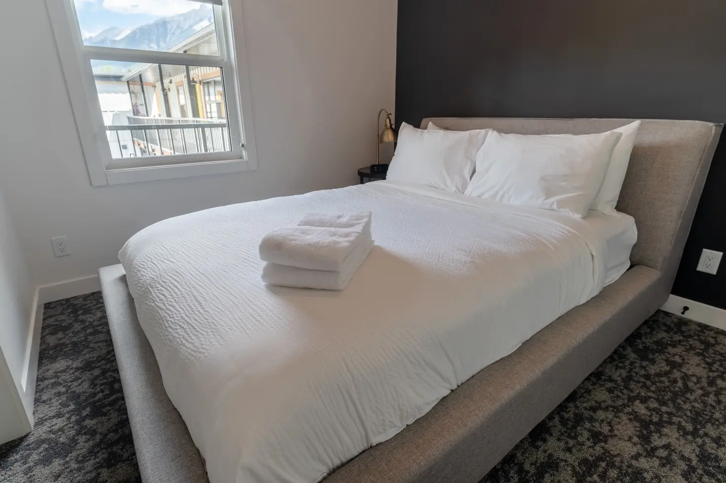 Canmore apartment bedroom with queen bed and mountain view window