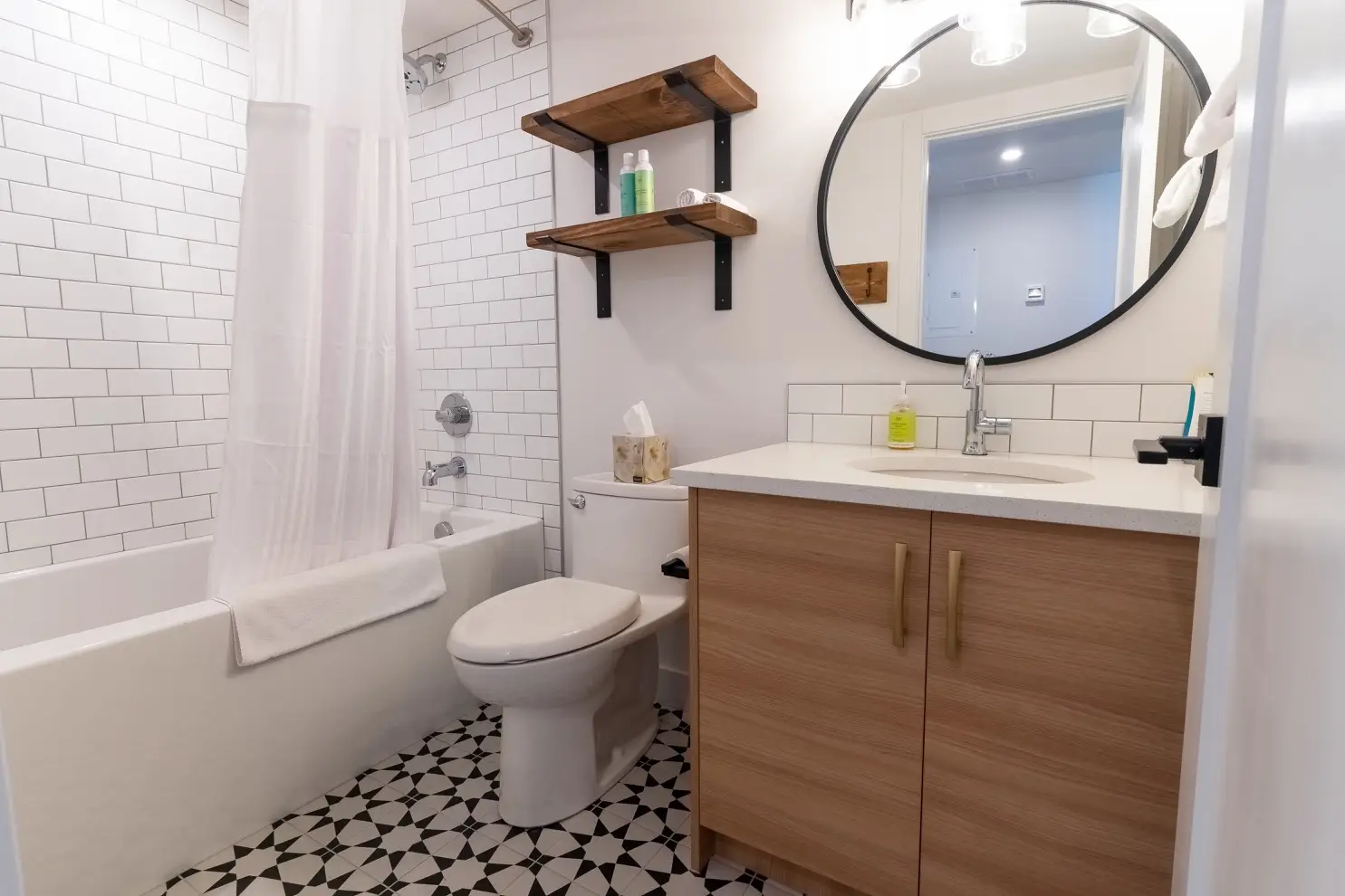 Modern bathroom with subway tile, wood vanity, and geometric floor in Basecamp Suites Canmore.