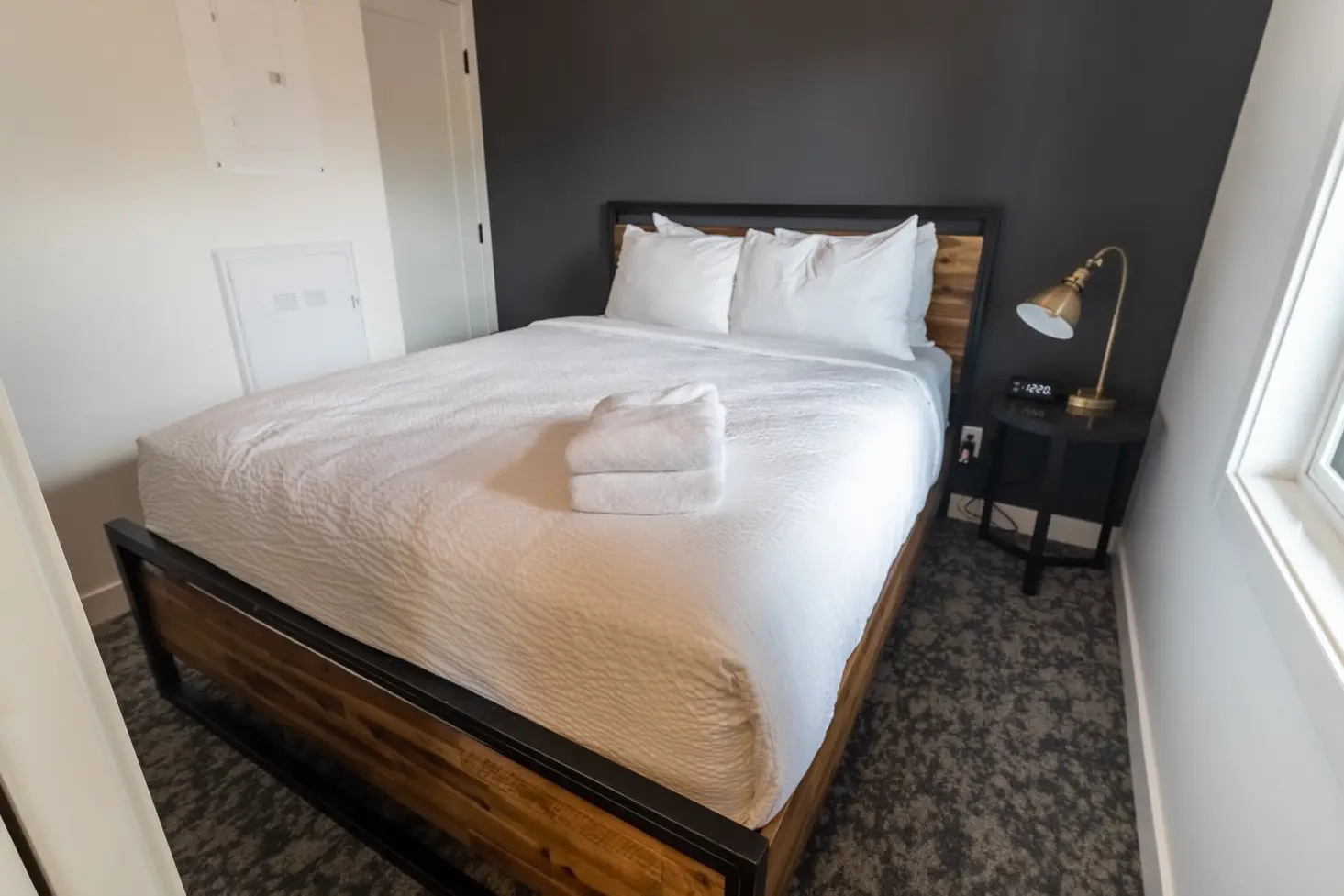 One bedroom suite at Basecamp Suites Canmore: a king-size bed with white linens and stacked towels.