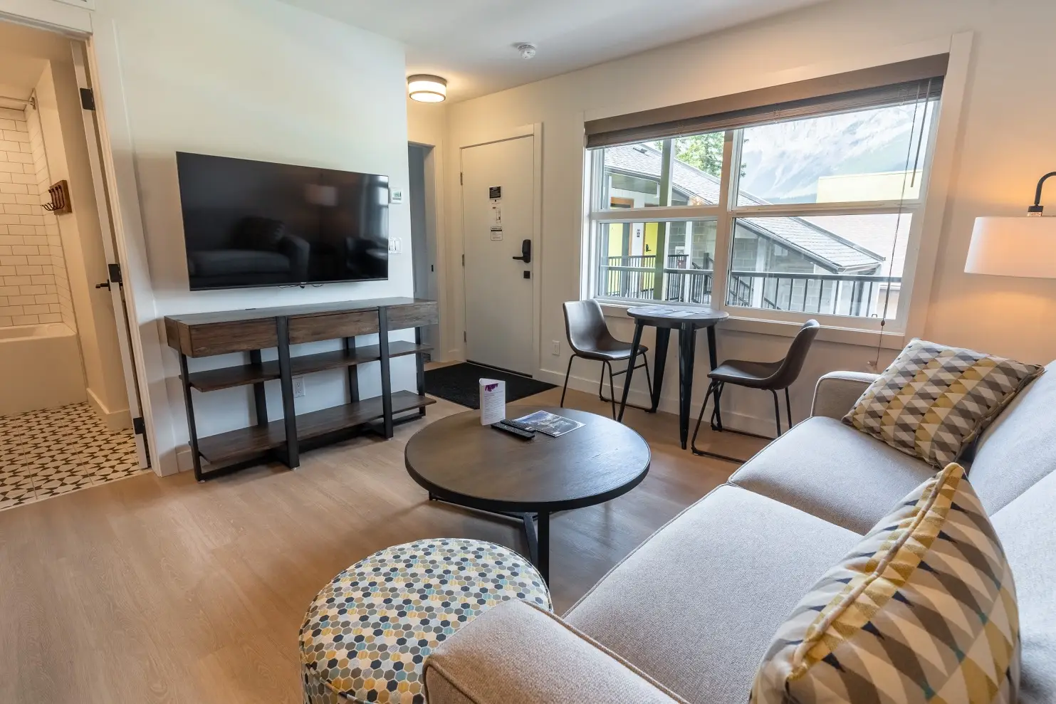 Basecamp Suites Canmore one-bedroom suite living area with sofa, coffee table, and TV.