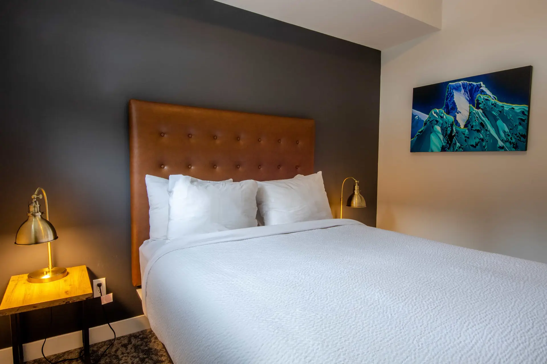 Revelstoke Three Bedroom Bunk Suite: Cozy bed with modern art and bedside lamps.