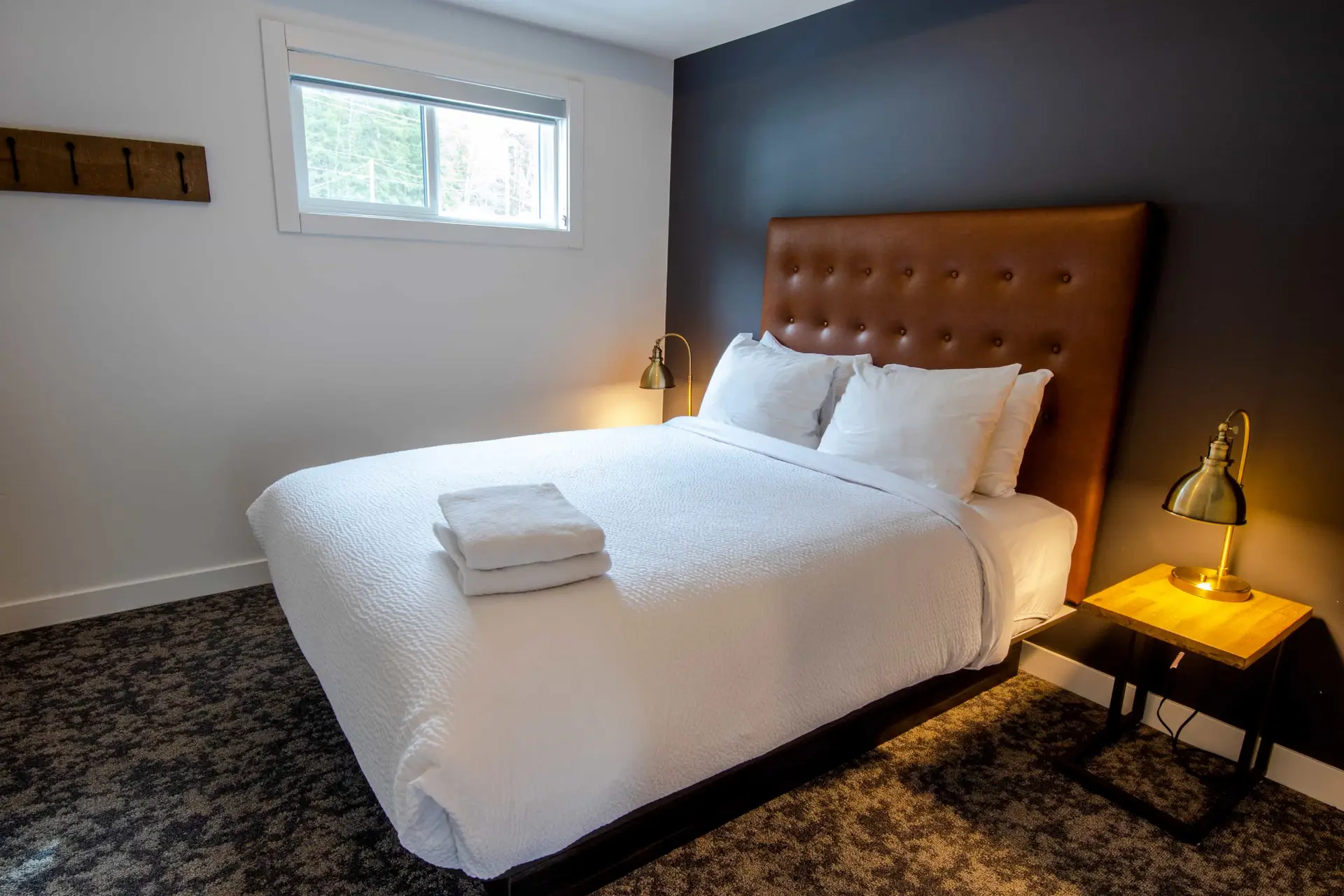 Comfortable bedroom with queen bed, white linens, and leather headboard at Basecamp Resorts Revelstoke.