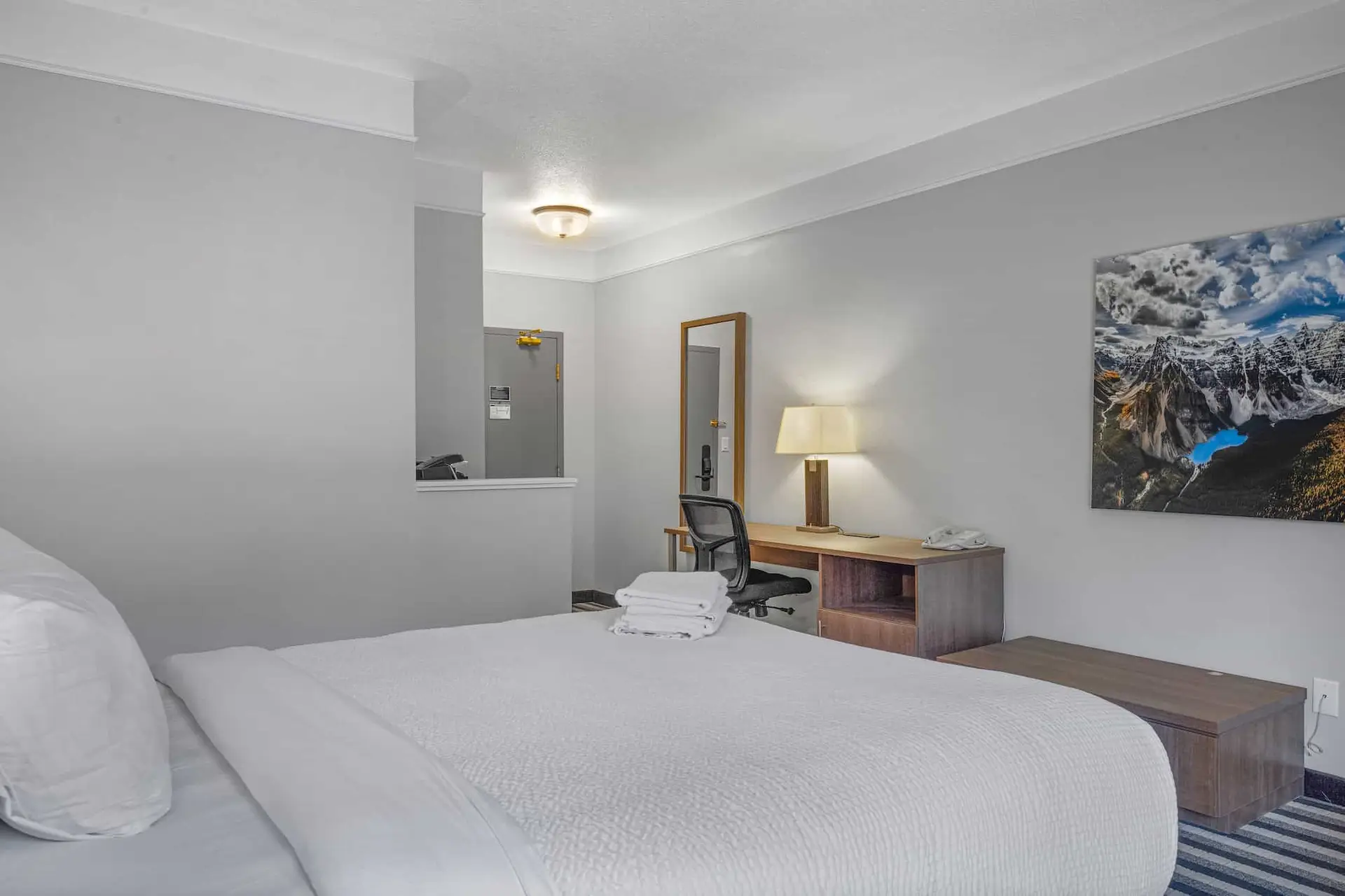Deluxe King room at Basecamp Northwinds Canmore with king bed, desk, and mountain art.