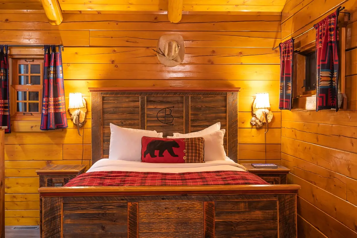 Cozy log cabin bedroom with a queen bed, bear motif decor, and rustic accents