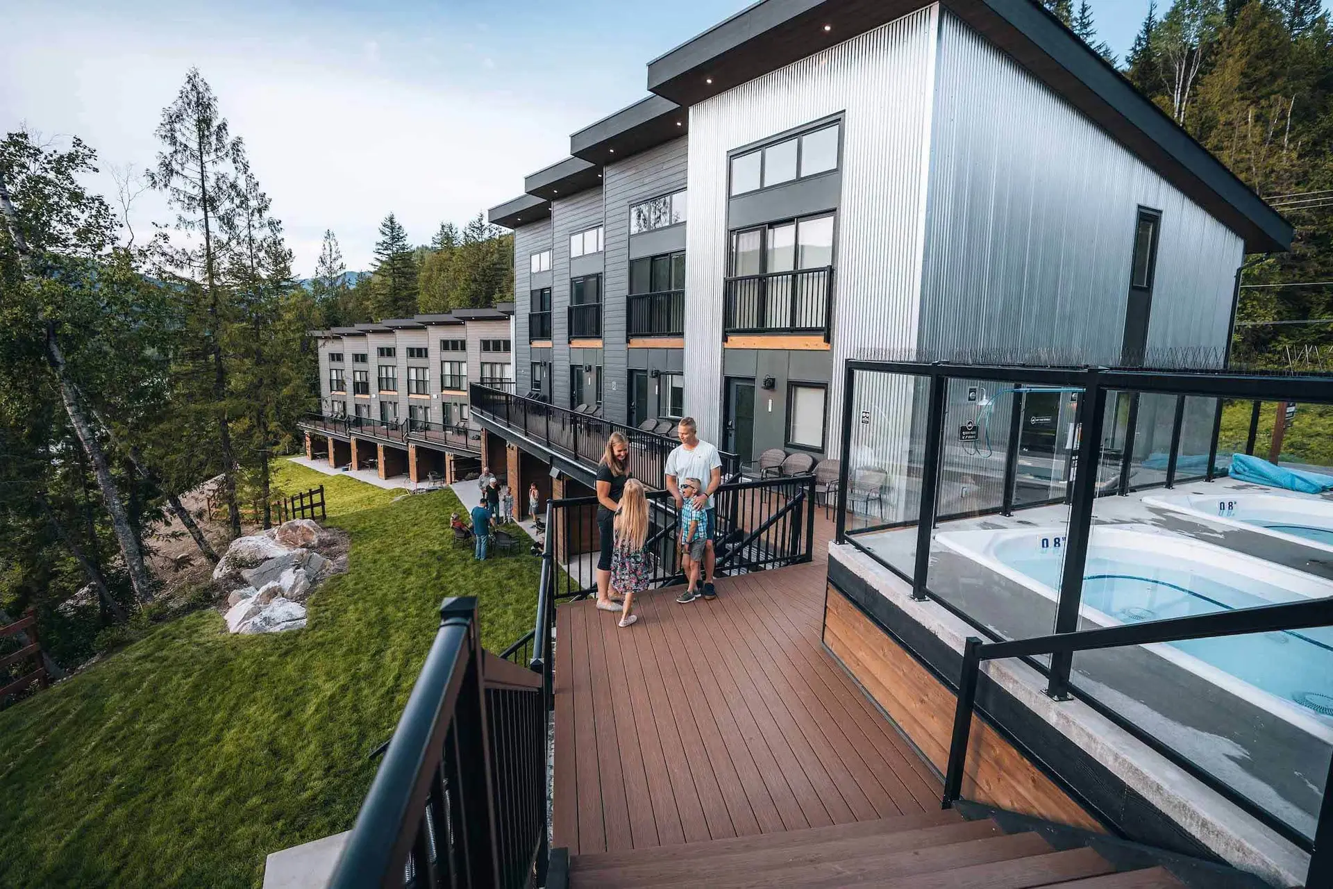 Family enjoying a hot tub at Revelstoke resort with modern architecture.