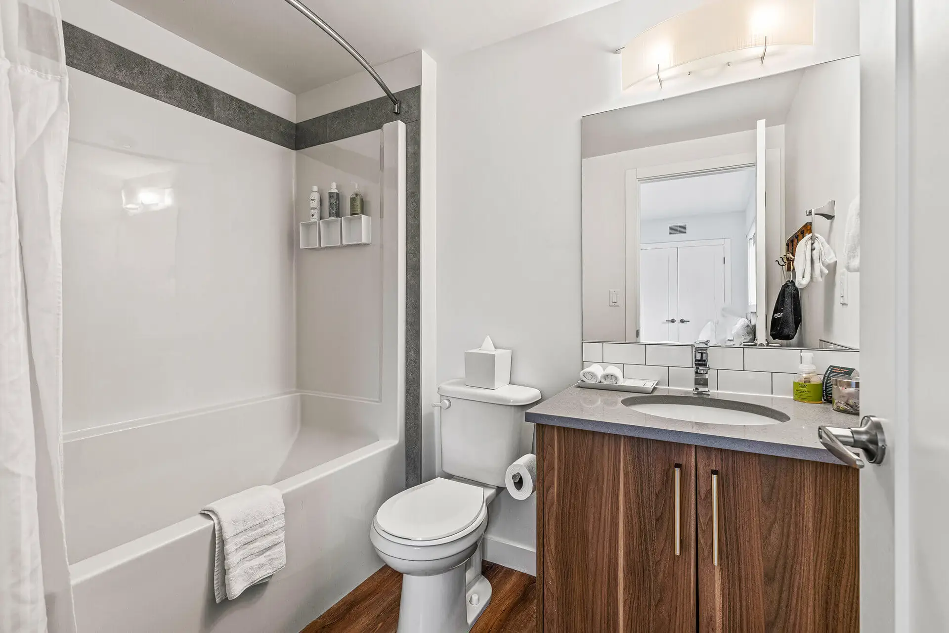 Modern bathroom with white tub, toilet, and wood vanity in Canmore resort suite.