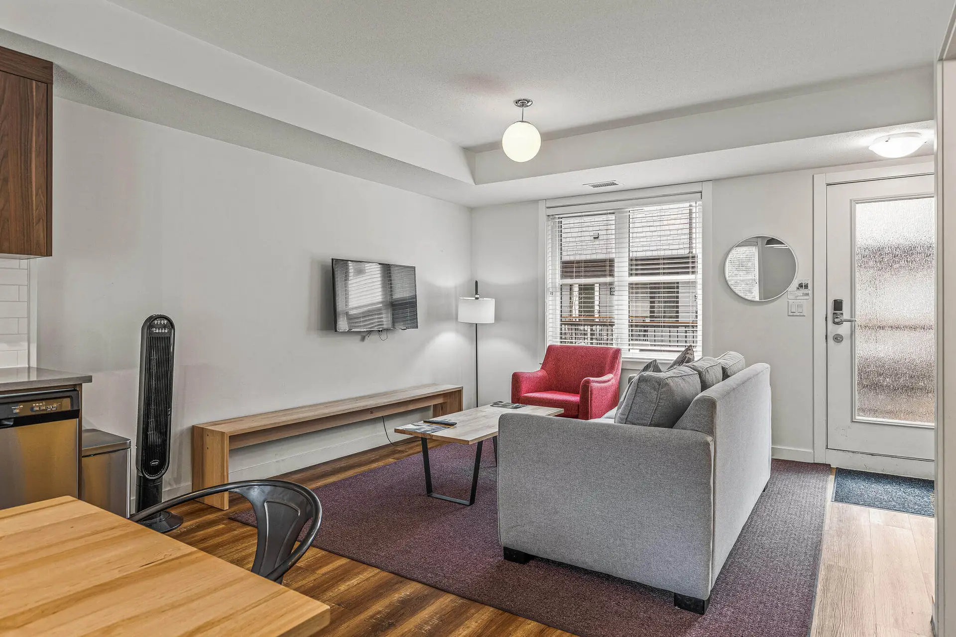 Living room of a Basecamp Resorts Canmore six-bedroom suite with sofa, armchair, and TV.