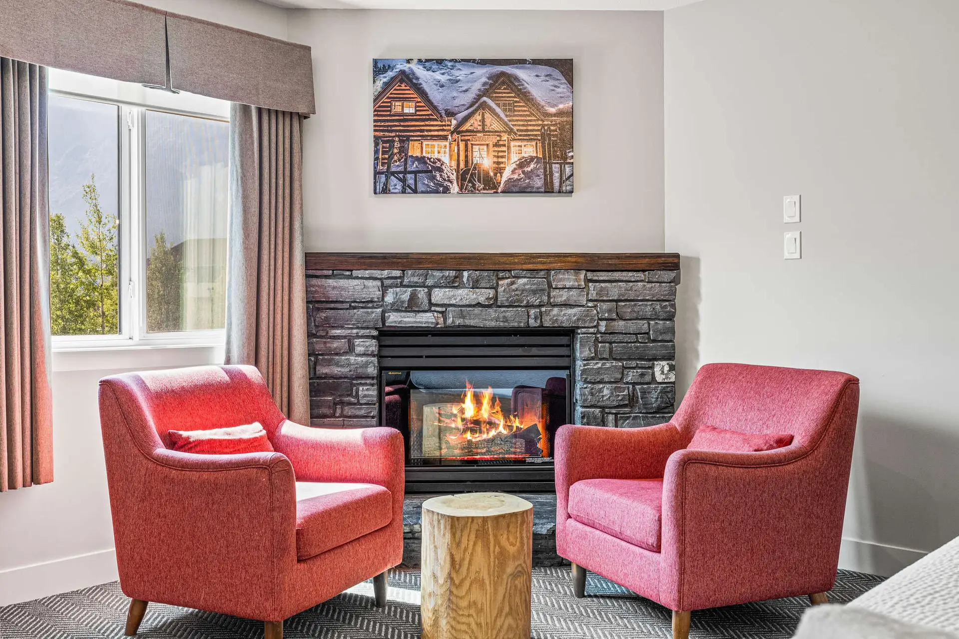 Cozy fireplace and red armchairs in Basecamp Lodge Canmore Deluxe Double King Room