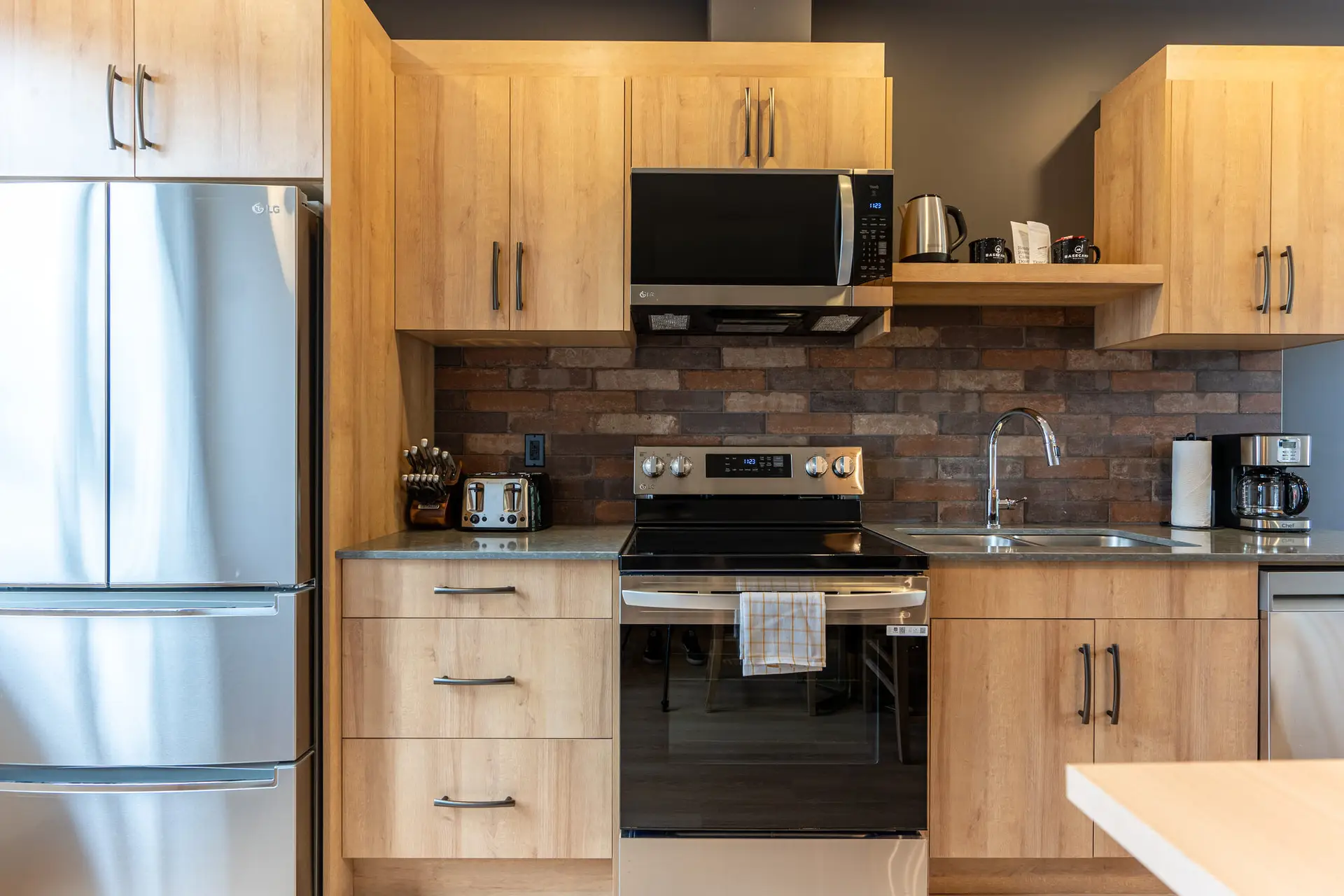 Modern kitchen in Basecamp Suites Revelstoke one bedroom suite with stainless steel appliances.