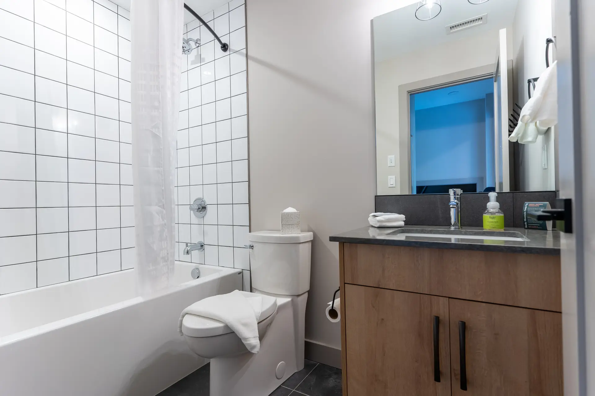 Modern bathroom in Basecamp Suites Revelstoke one bedroom suite with white tiled shower.