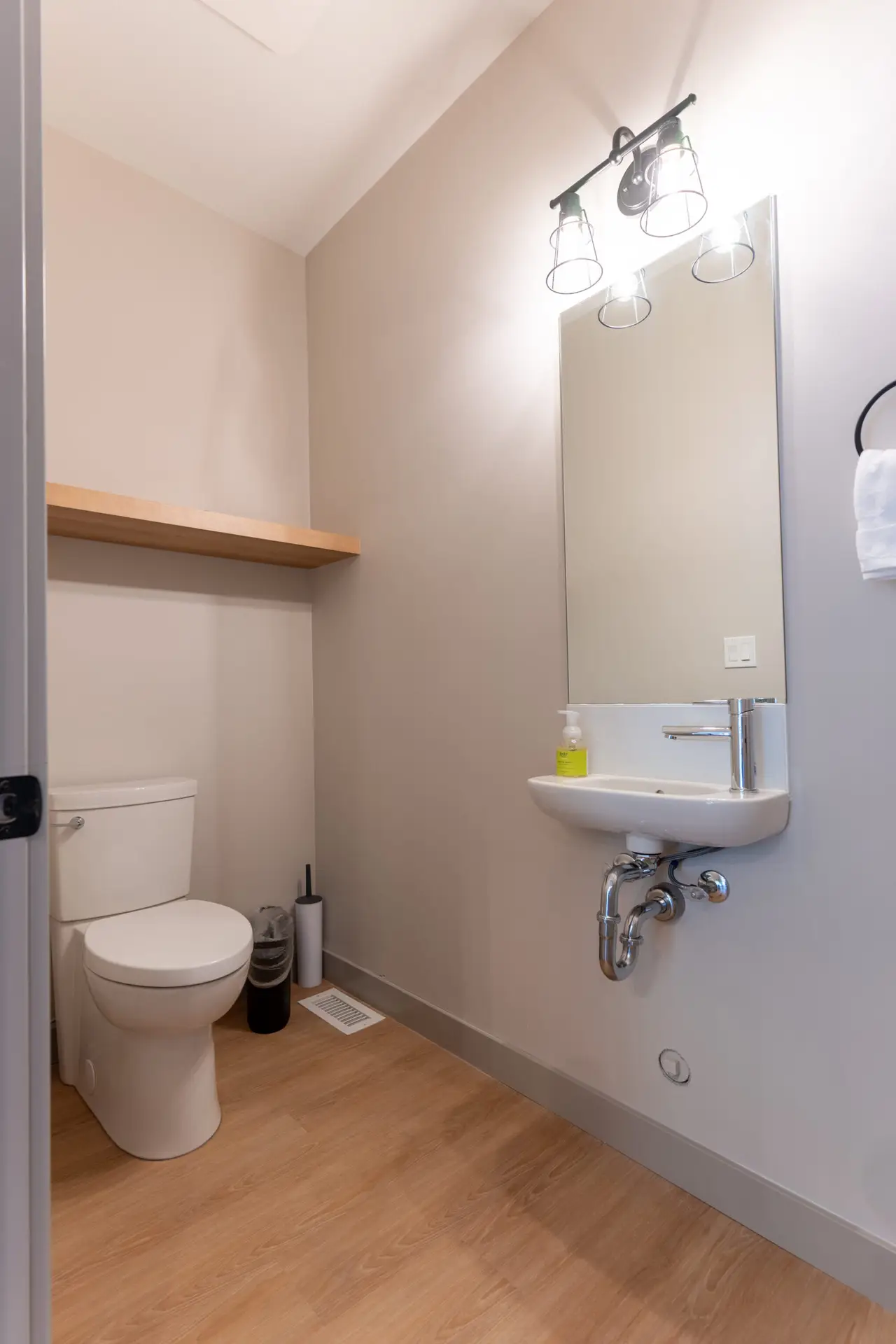 Modern powder room with toilet, sink, and shelf in a hotel suite.