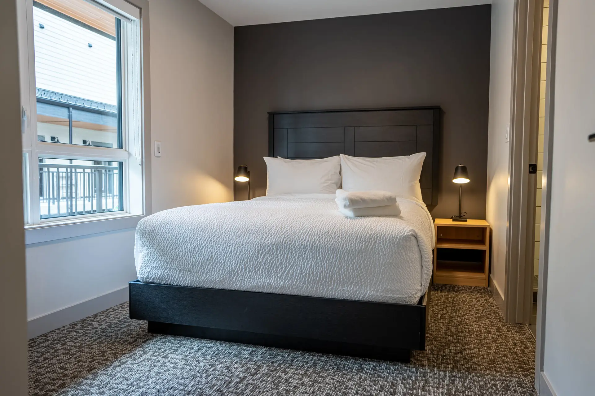 Modern hotel bedroom with king-size bed and dark accent wall