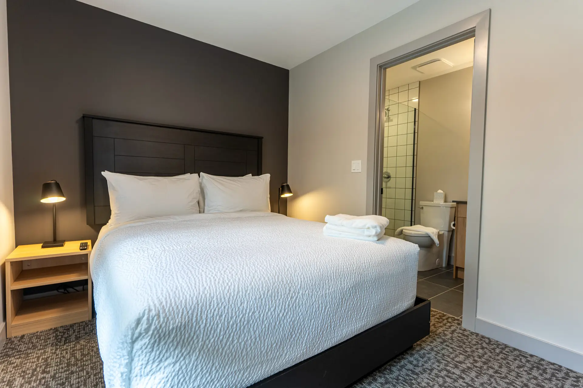 Basecamp Suites Revelstoke six-bedroom suite: king bed, modern decor, ensuite bathroom.