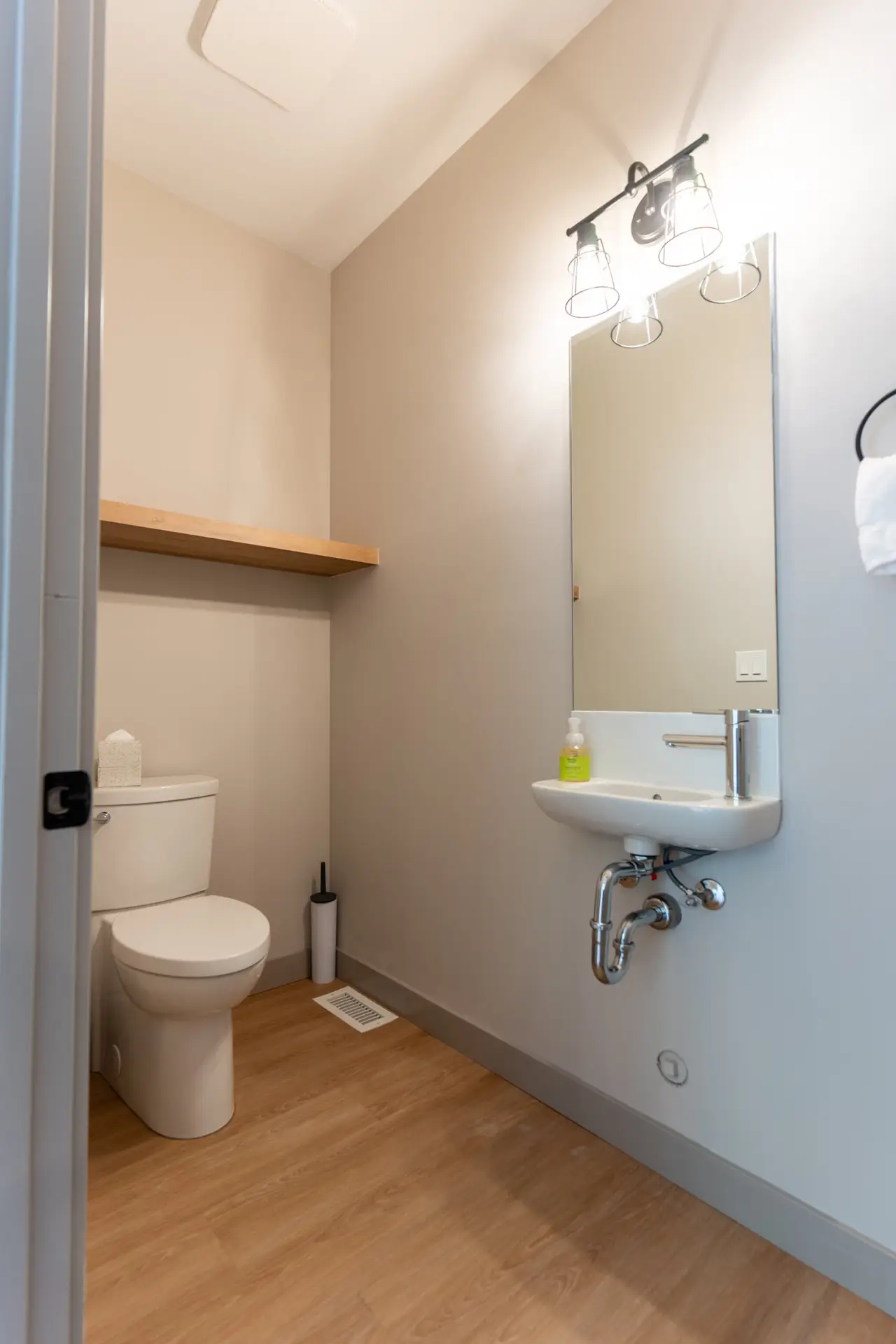 Modern bathroom with toilet, sink, and shelf in Basecamp Suites Revelstoke
