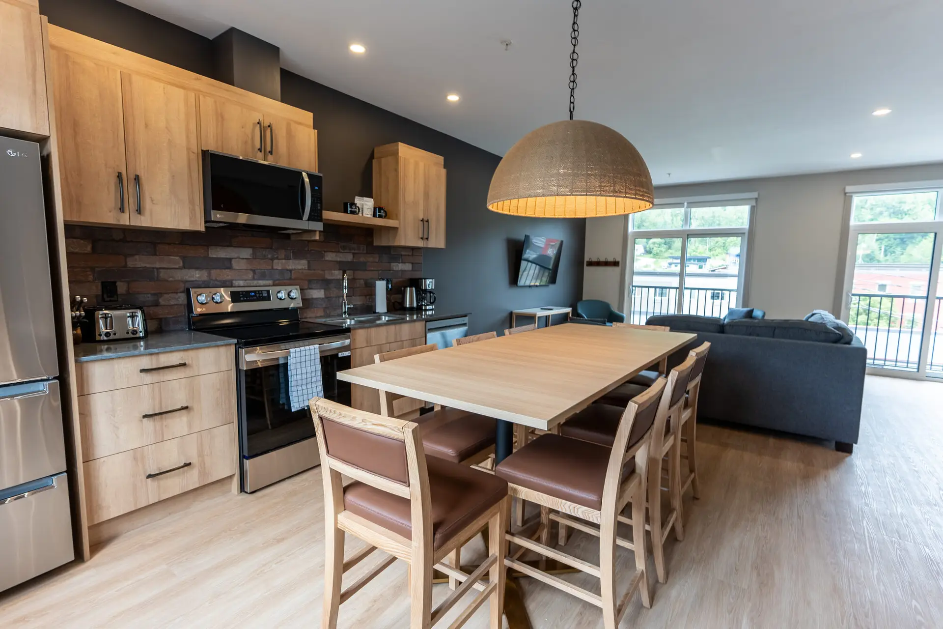 Modern kitchen and dining area in a Revelstoke suite with blonde wood cabinets