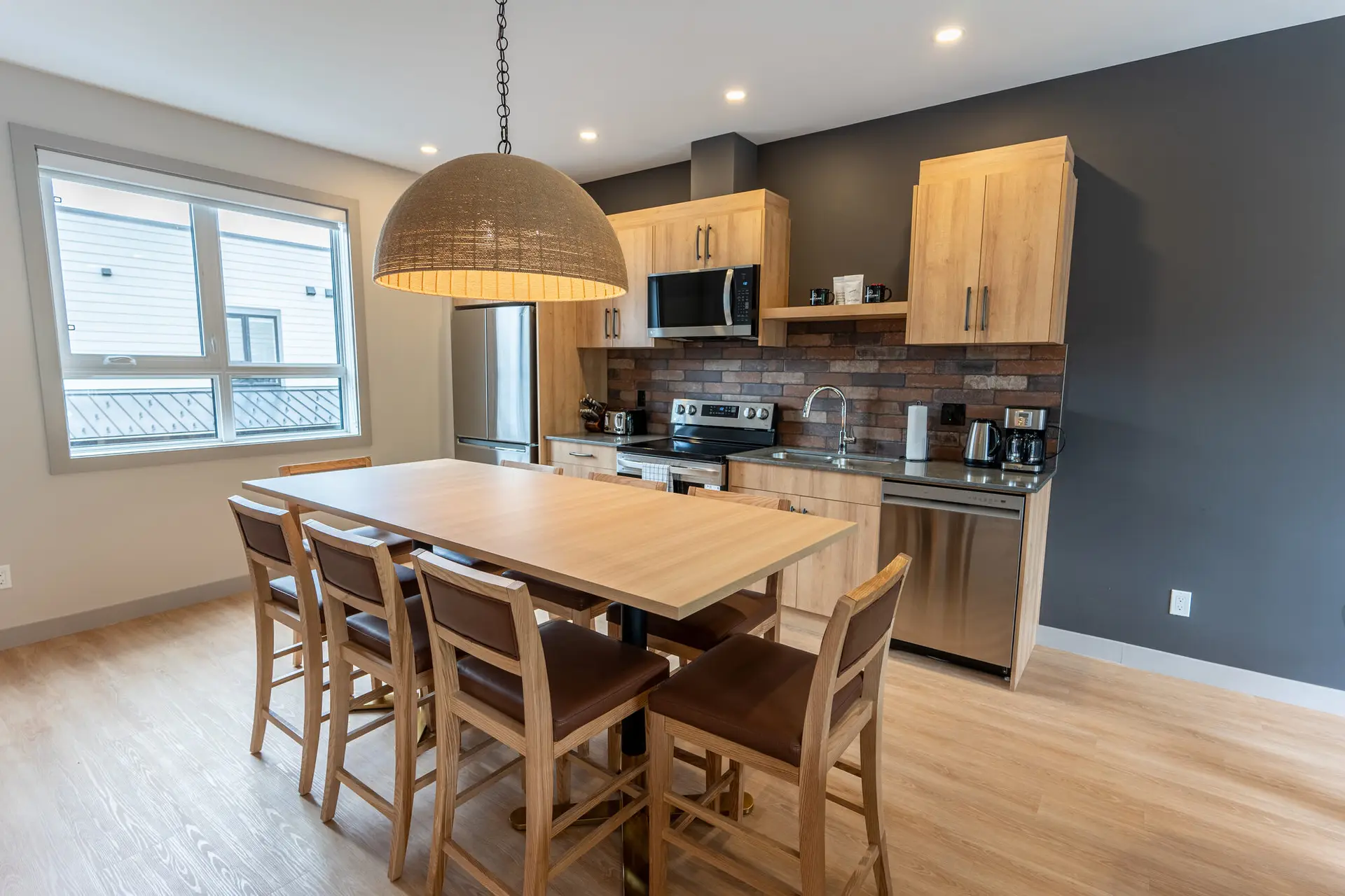 Modern kitchen and dining area in Basecamp Suites Revelstoke, featuring wood cabinets and island seating.