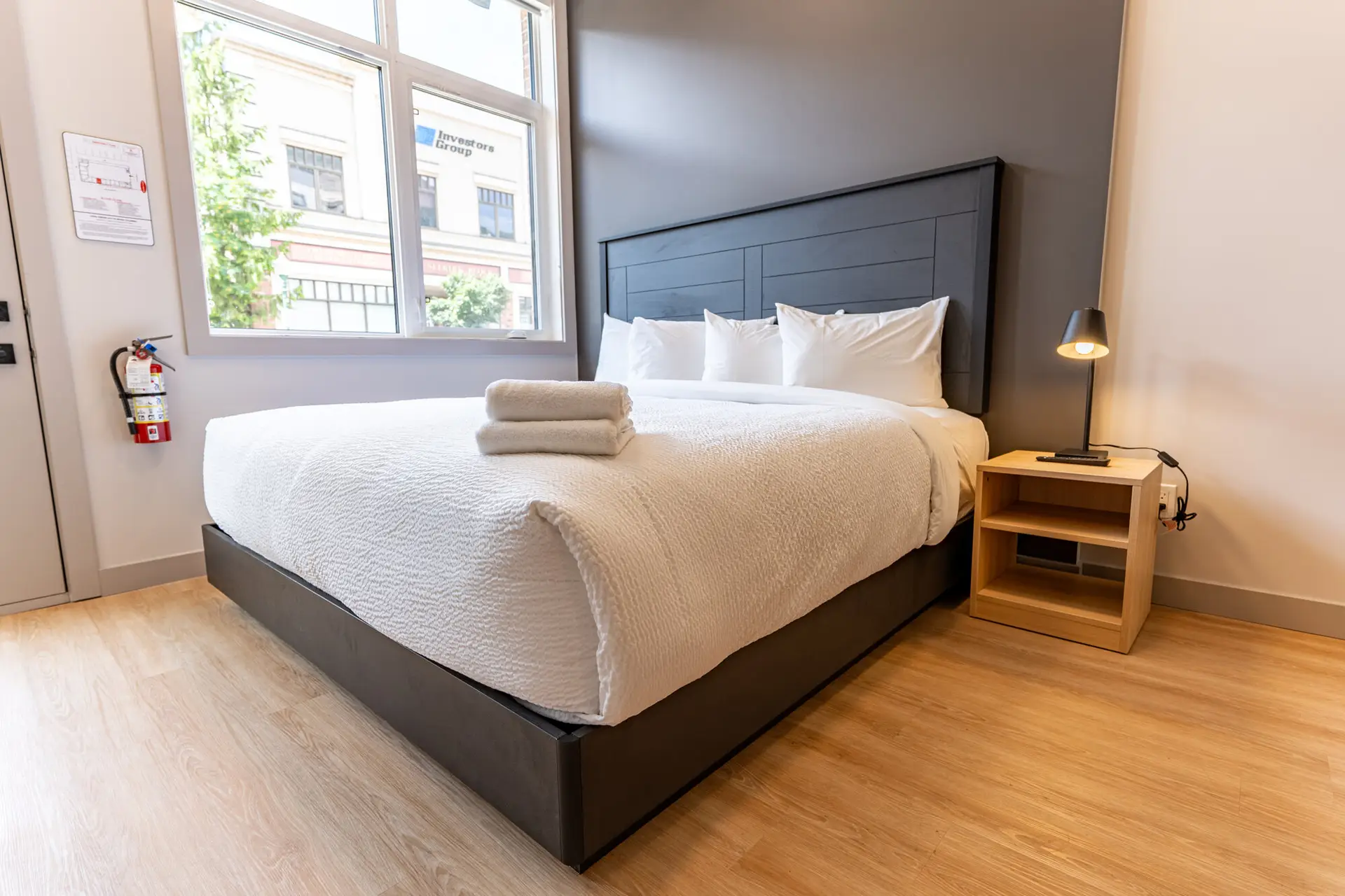 King-size bed with white linens and pillows in a modern hotel room.