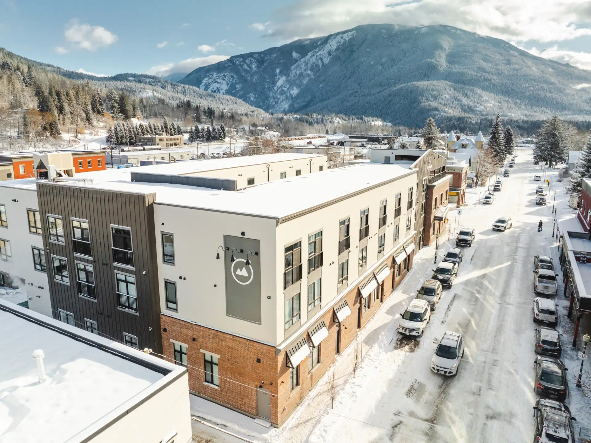 Basecamp Suites Revelstoke exterior in winter with snow-covered mountains.