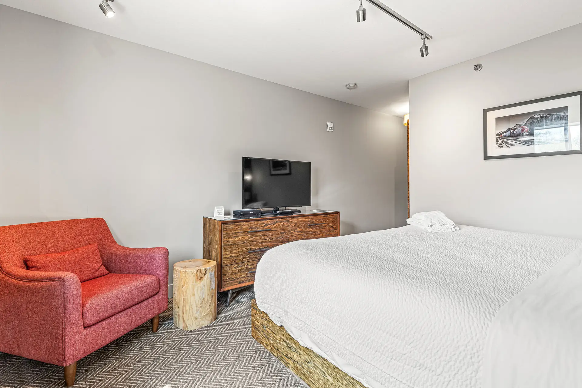 King room at Basecamp Lodge Canmore with red armchair, TV, and bed