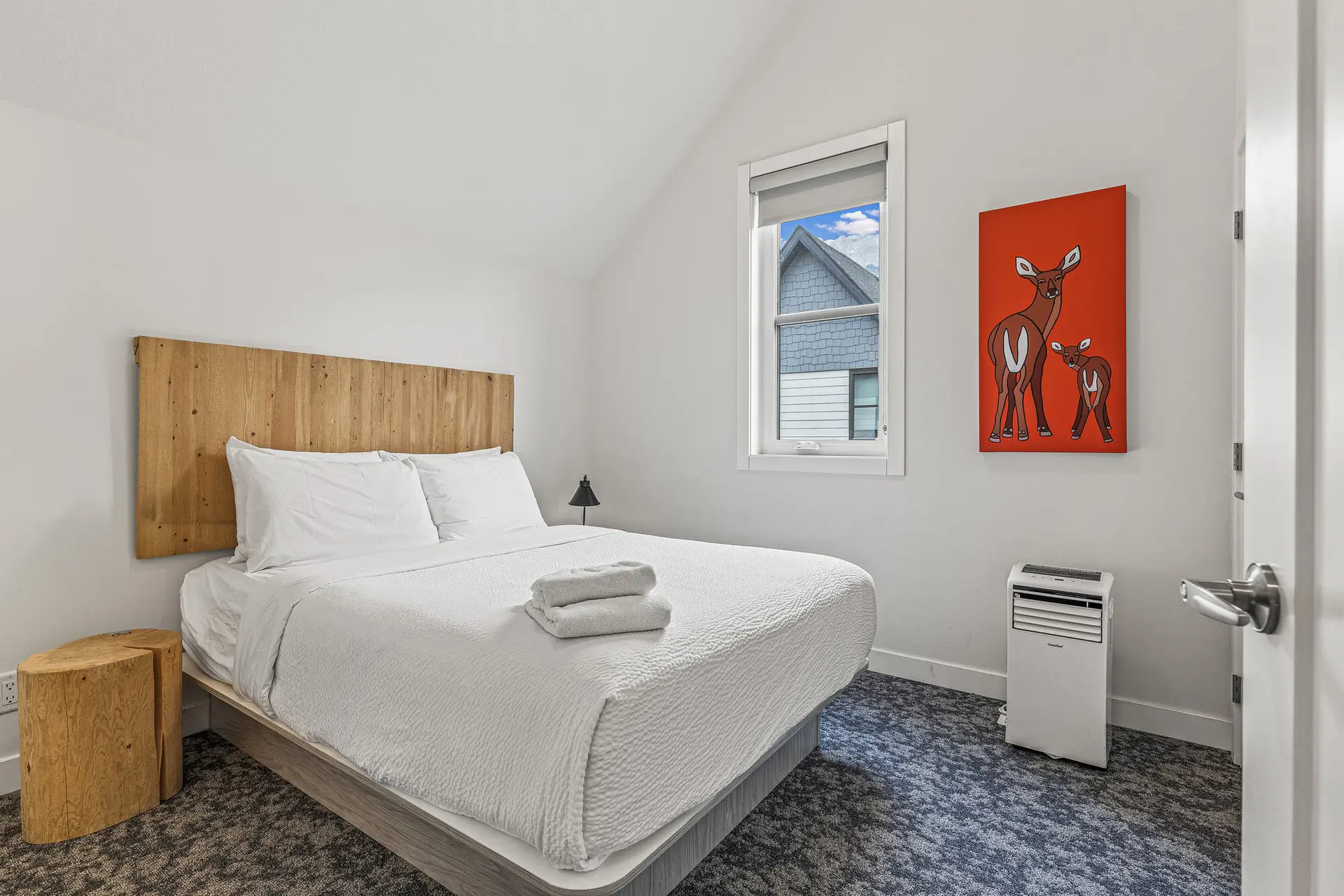 Canmore two-bedroom suite bedroom with queen bed, deer art, and window view