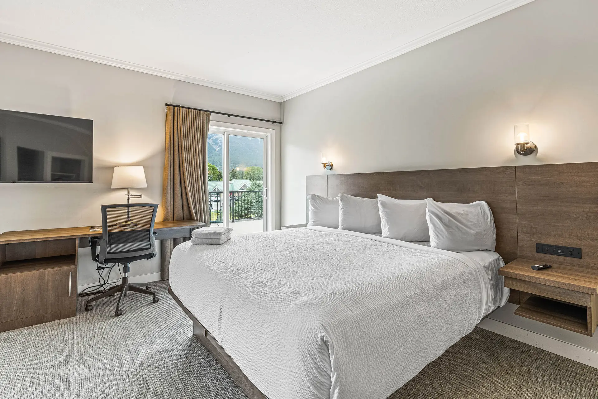 Basecamp Northwinds Canmore family room with king bed, desk, and balcony view.