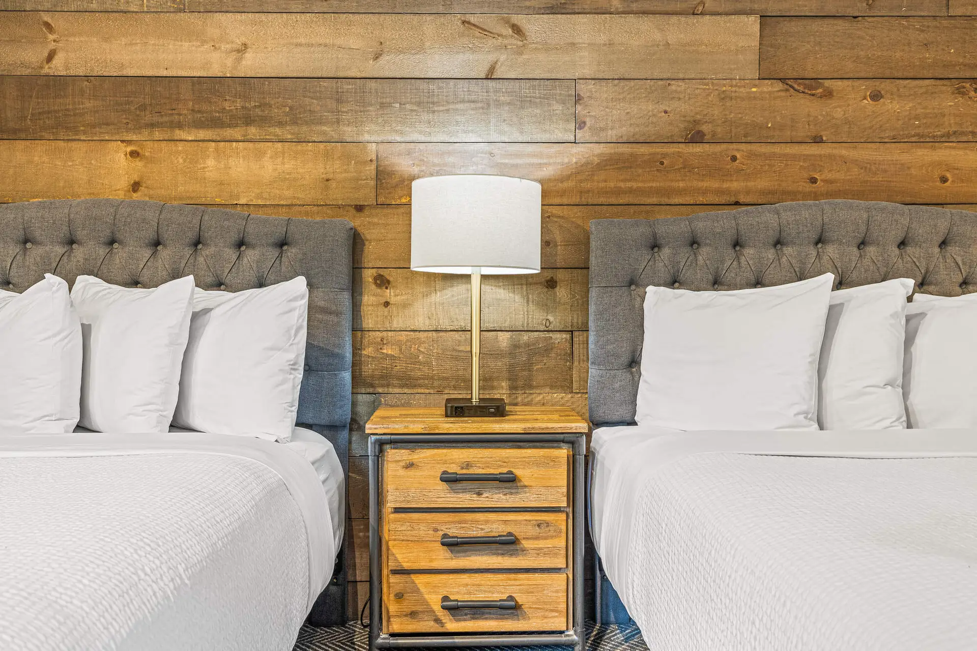 Basecamp Lodge Canmore Double Queen room with two beds and wood-paneled wall.