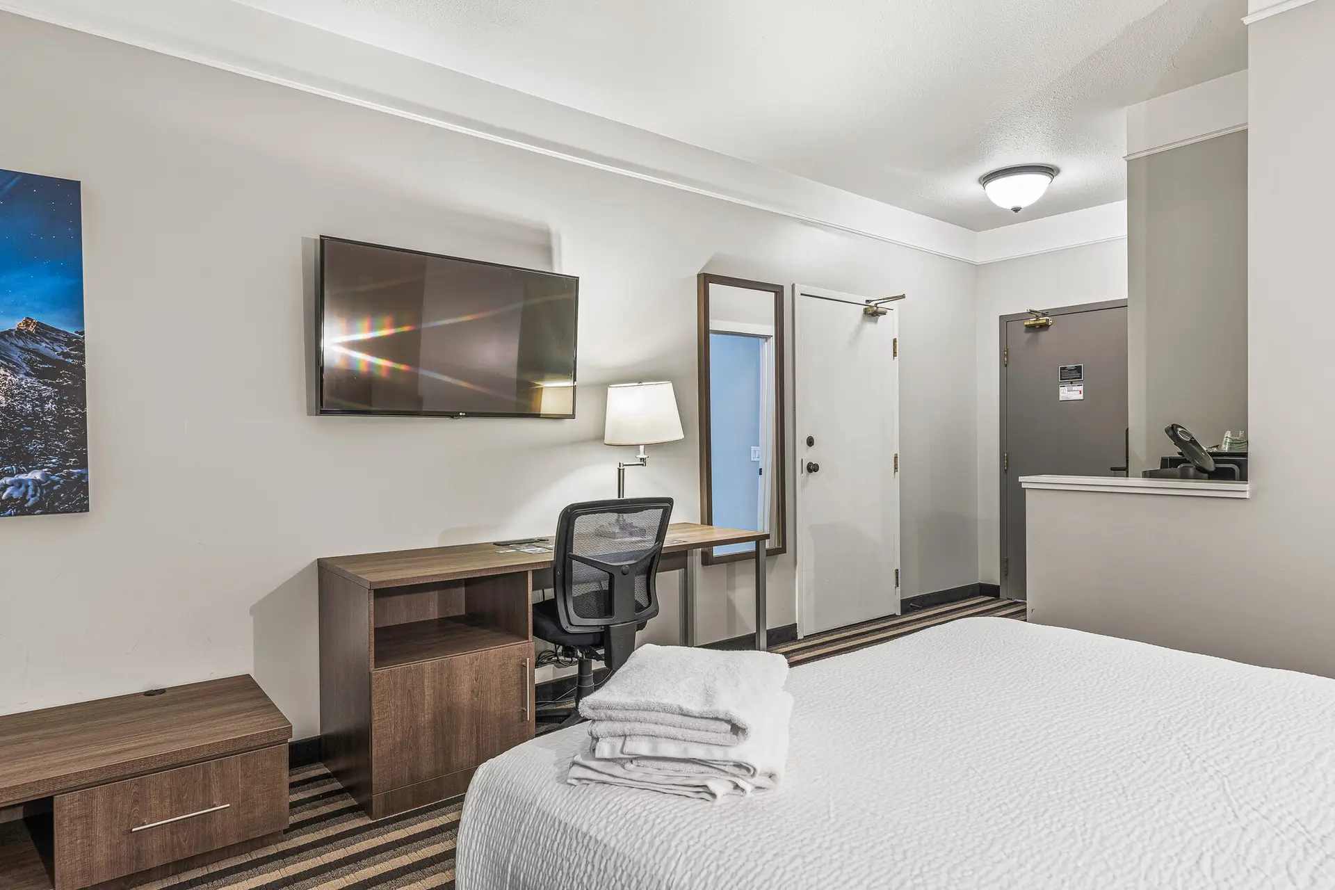 Deluxe Double Queen room at Basecamp Northwinds Canmore with desk, TV, and bed.