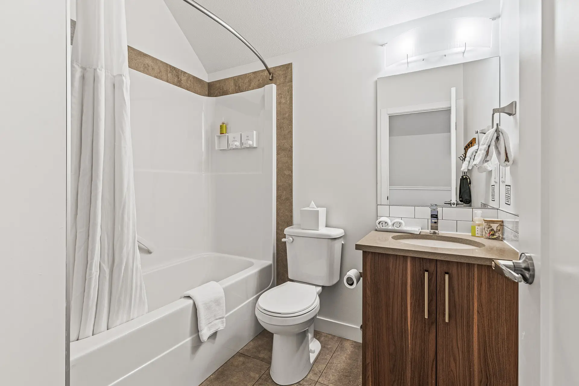 Modern bathroom in a Basecamp Resorts Canmore two-bedroom suite, featuring a tub/shower combo and vanity.