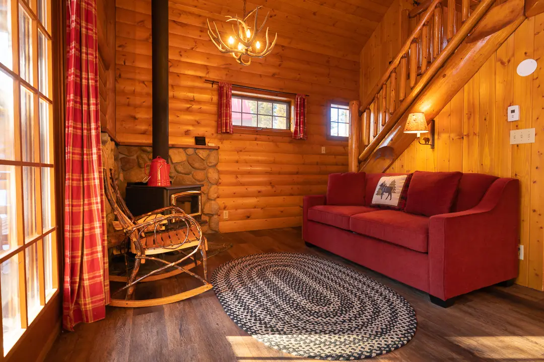 Cozy cabin living room with red sofa, rocking chair, and wood stove