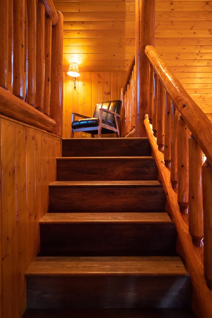 Interior view of a wooden cabin staircase with a chair and lamp