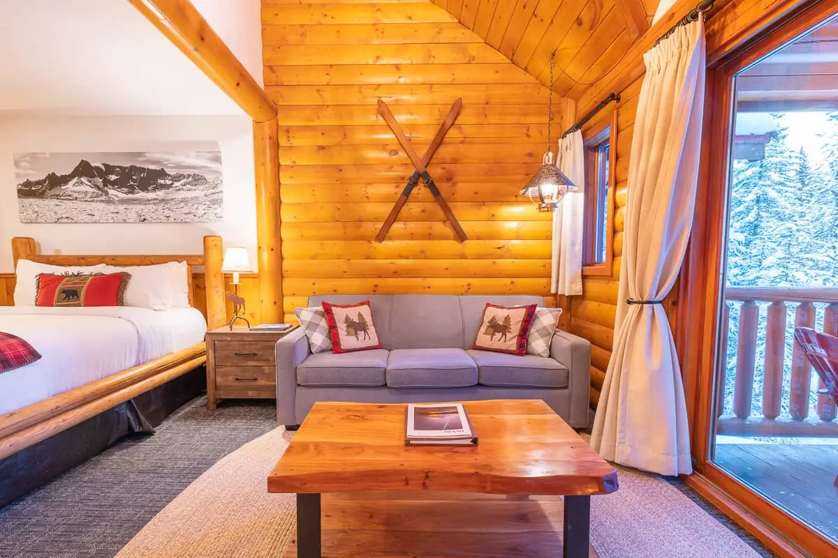 Basecamp Baker Creek Jacuzzi Suite: cozy log room with bed, sofa, coffee table.
