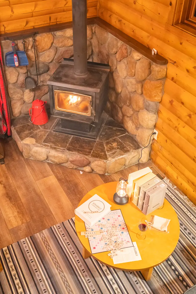 Cozy cabin living room with stone fireplace, wood walls, and a game table