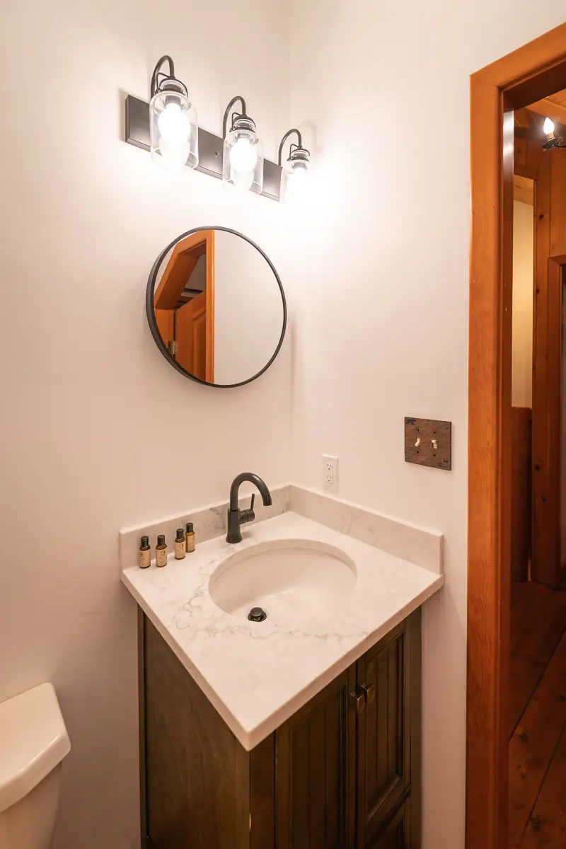 Basecamp Baker Creek Jacuzzi Suite bathroom vanity with sink, mirror, and light fixture.