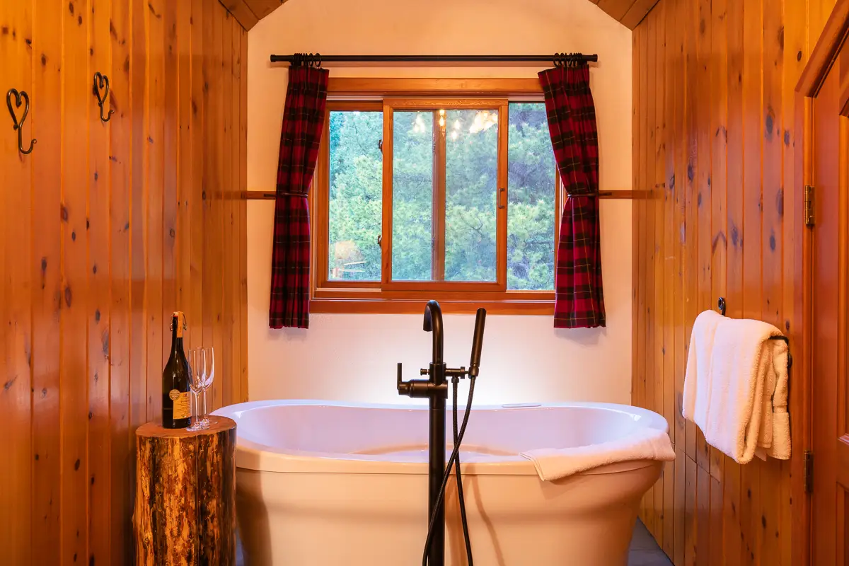 Luxurious Jacuzzi tub in Basecamp Baker Creek's Superior Suite with champagne.
