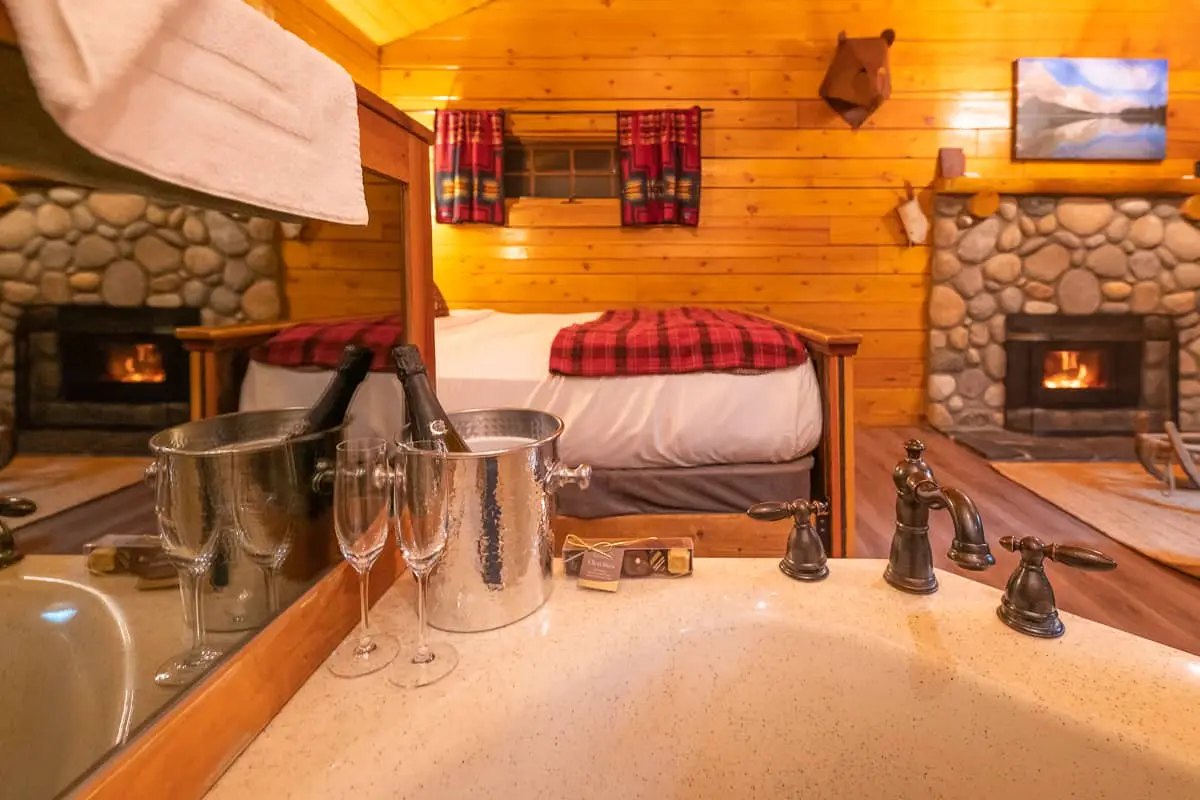 Basecamp Baker Creek Queen Cabin: Luxurious bathtub with champagne and fireplace view.