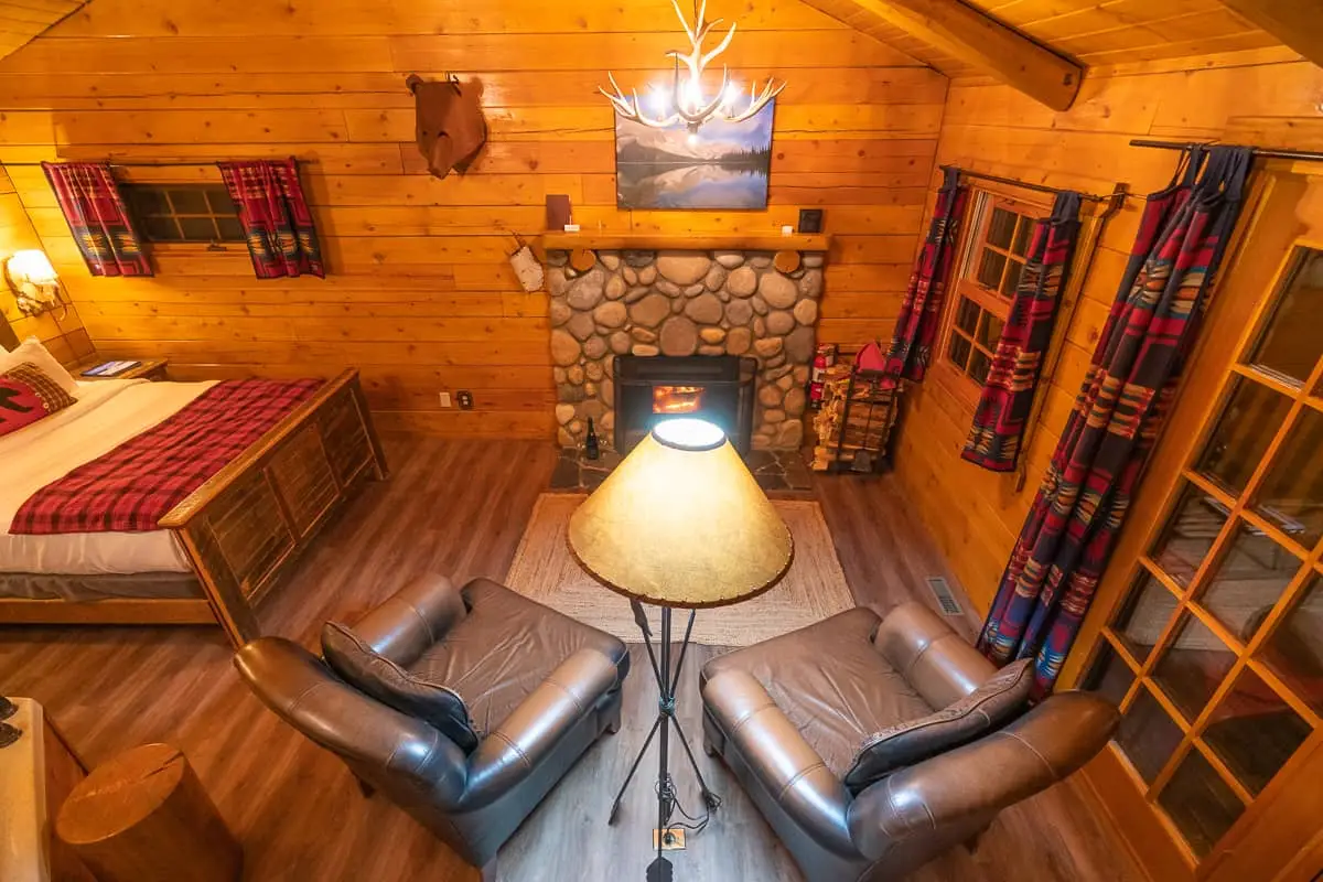 Cozy Baker Creek Queen Cabin living area with fireplace, leather chairs, and queen bed.
