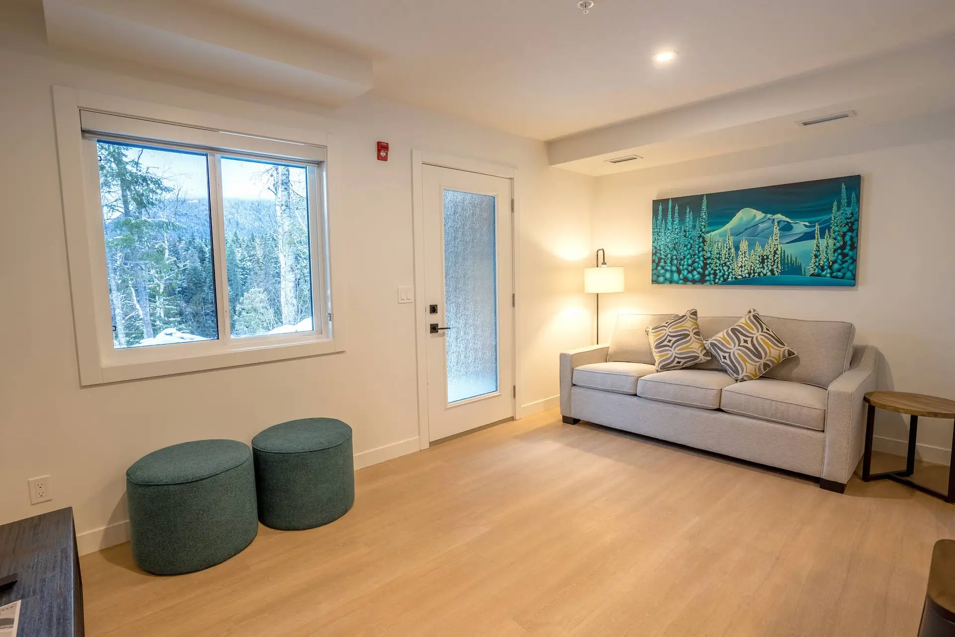 Revelstoke one bedroom suite living area with sofa, art, and window view