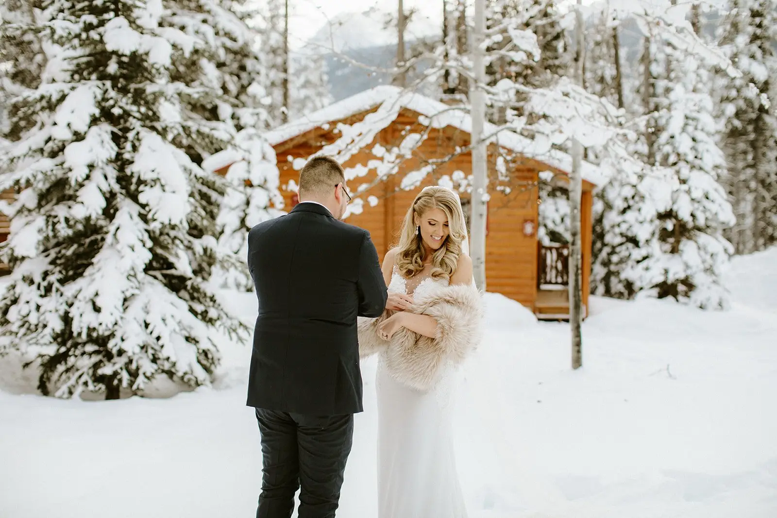 Bride and groom in winter wedding attire at Baker Creek, Banff