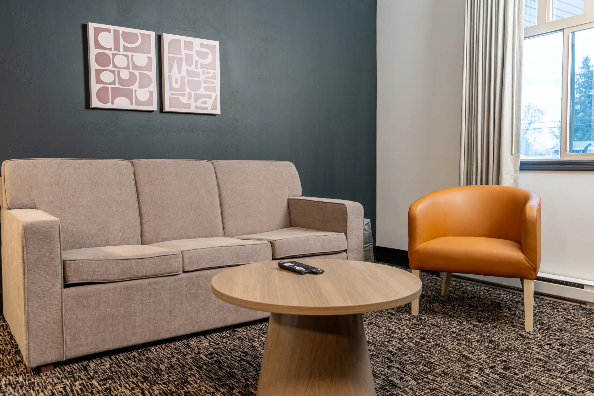 Revelstoke suite living area: beige sofa, orange chair, coffee table, art