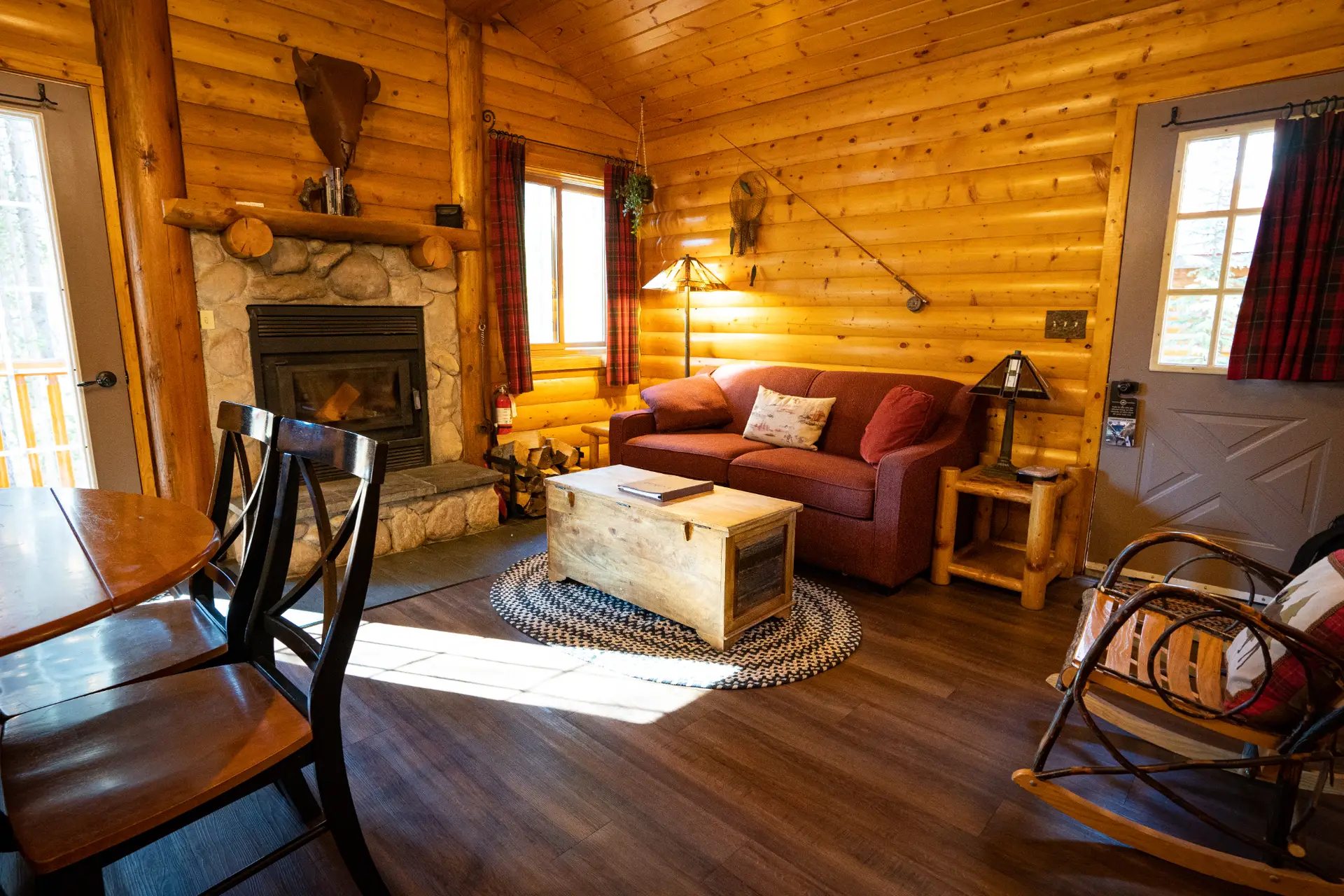 Interior of a cozy log cabin living room with fireplace, sofa, and dining table.