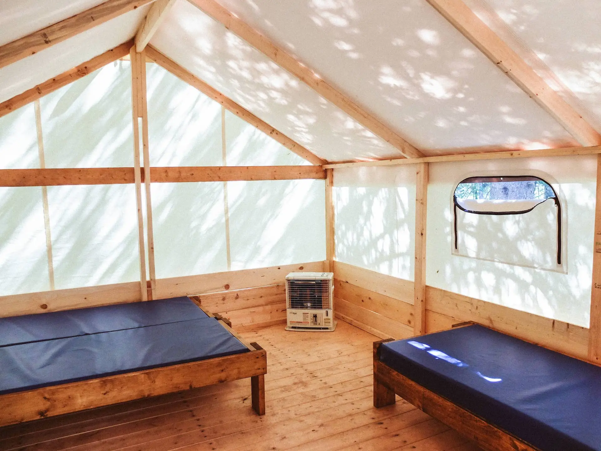 Interior of a Basecamp Sundance Riverside trapper tent with two beds and a heater.
