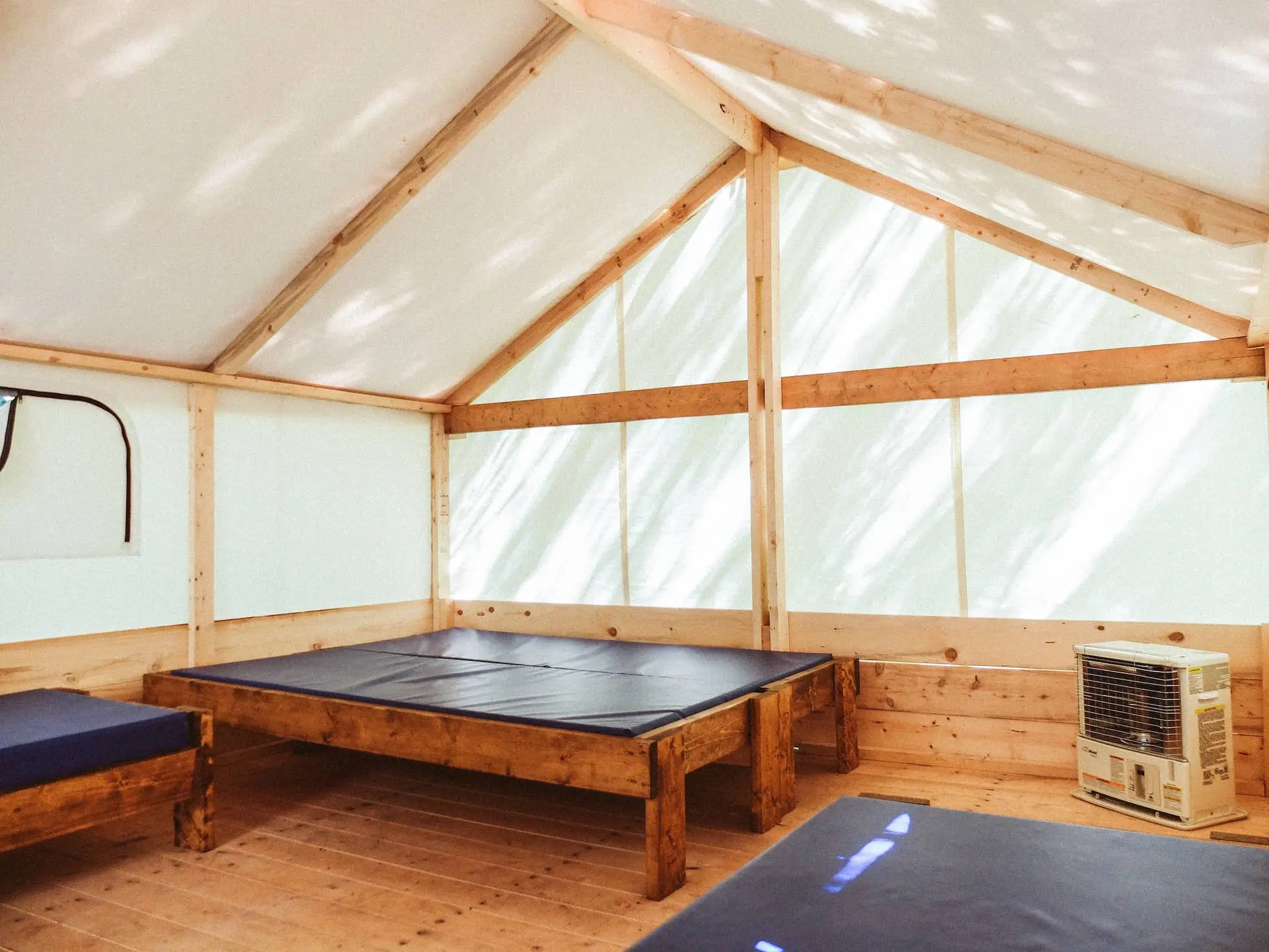 Interior of a Sundance Riverside trapper tent with wooden beds and a heater.