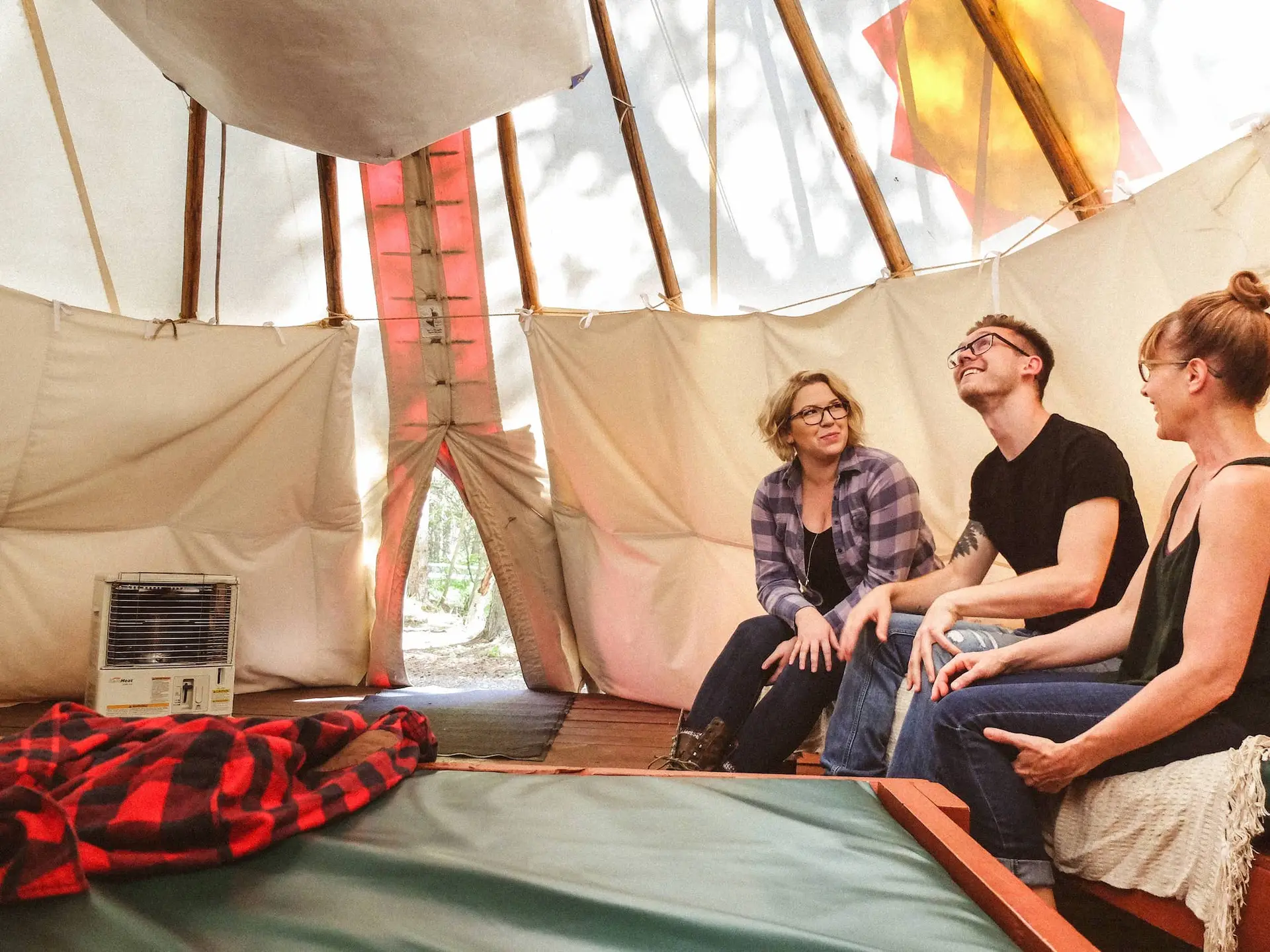 Family enjoying conversation inside a cozy Basecamp Sundance tipi.