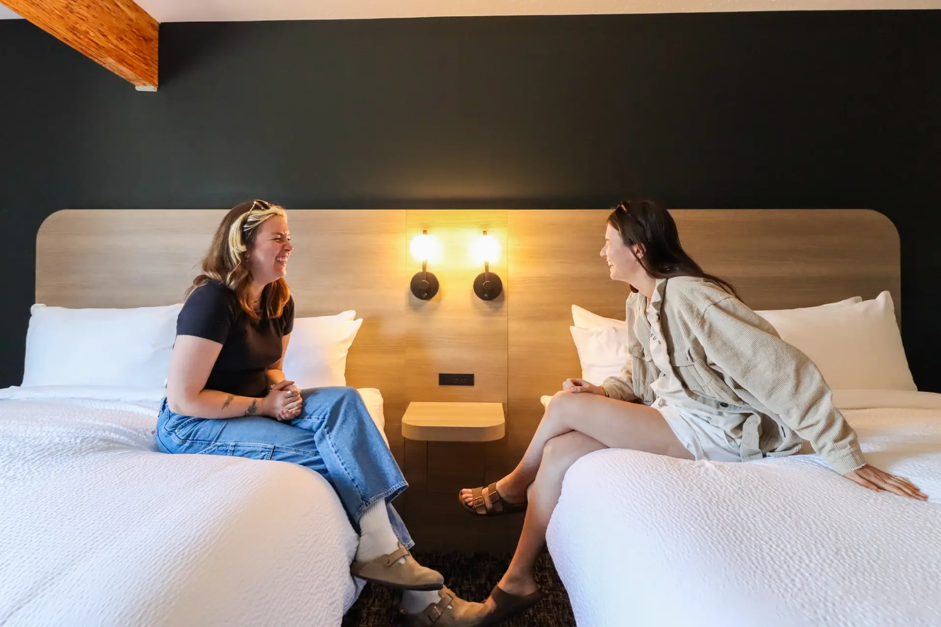 Two women chat in a hotel room at Revelstoke Northwinds, ideal for group bookings.